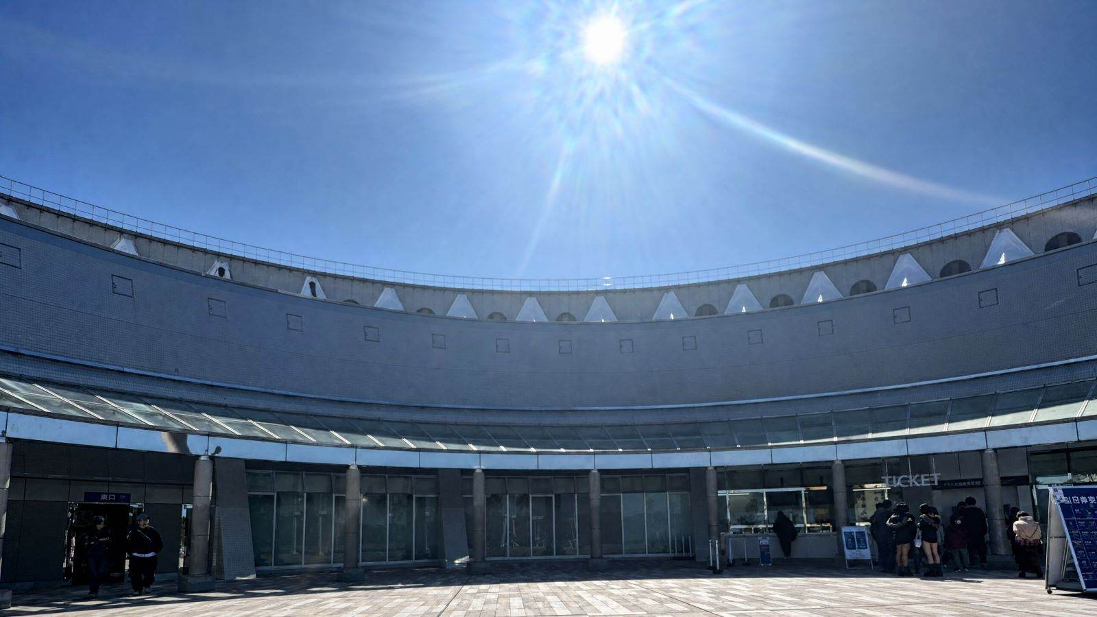 日本福岡海之中道海洋世界，弧形的現代建築外觀及陽光灑落的入口廣場。
