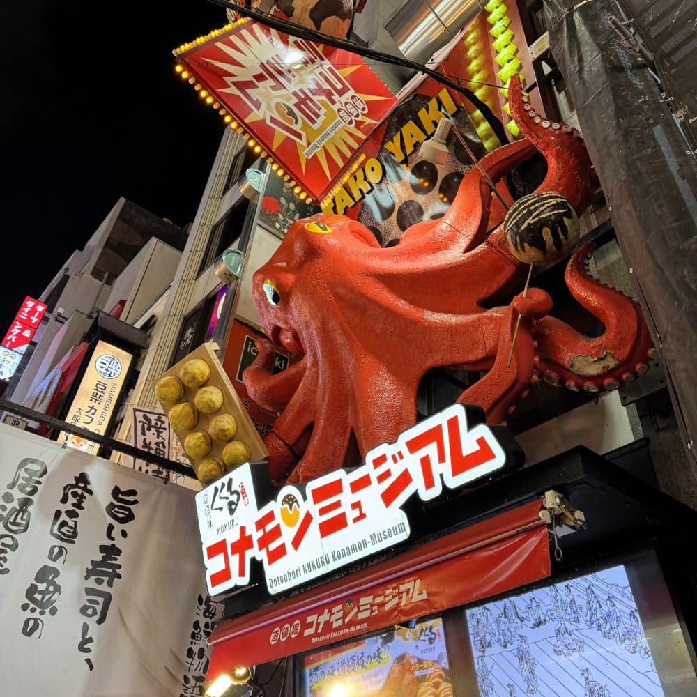 Famous giant 3D red octopus sculpture holding a takoyaki ball at the Dotonbori Kukuru Konamon Museum in Osaka, Japan.