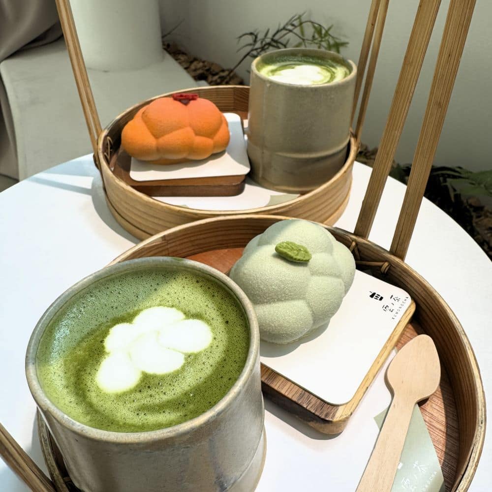 Signature cloud-shaped mousse cakes and Uji matcha lattes with cloud foam art served on bamboo trays at Kumonocha Cafe (雲ノ茶) in Arashiyama, Kyoto, Japan.