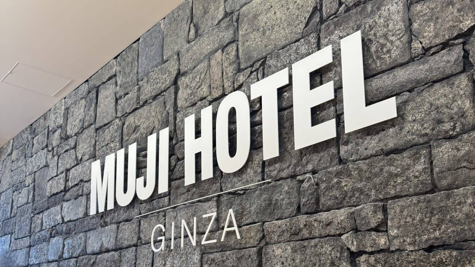 日本東京 MUJI HOTEL GINZA 內，深色石牆上的 MUJI HOTEL GINZA 標誌特寫。