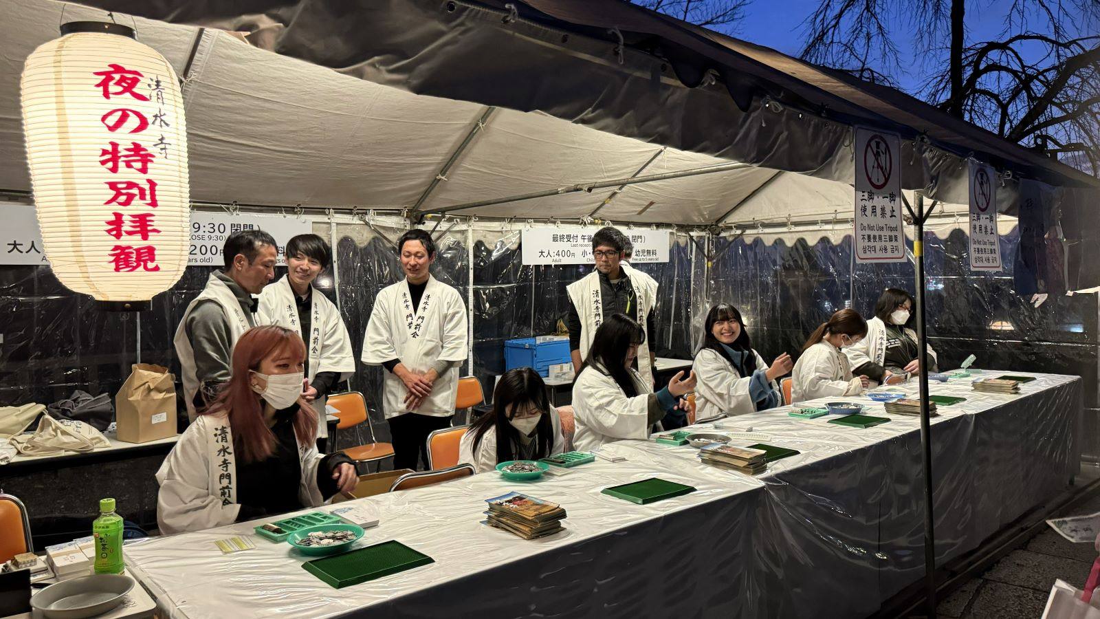 Staff selling entrance tickets at the illuminated canopy booth for the Special Night Viewing event at Kiyomizu-dera Temple in Kyoto, Japan.