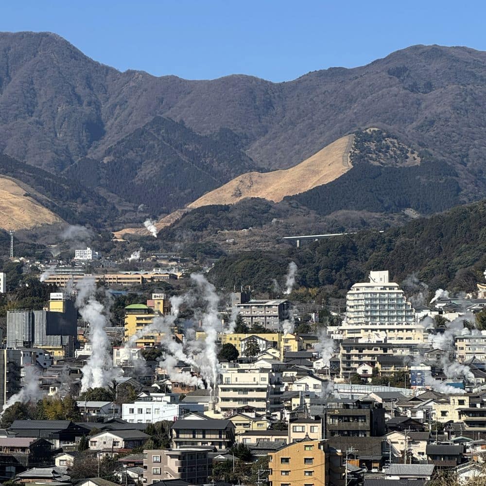 日本九州大分縣別府溫泉市全景,溫泉冒出的地熱蒸氣在鶴見岳前升起。